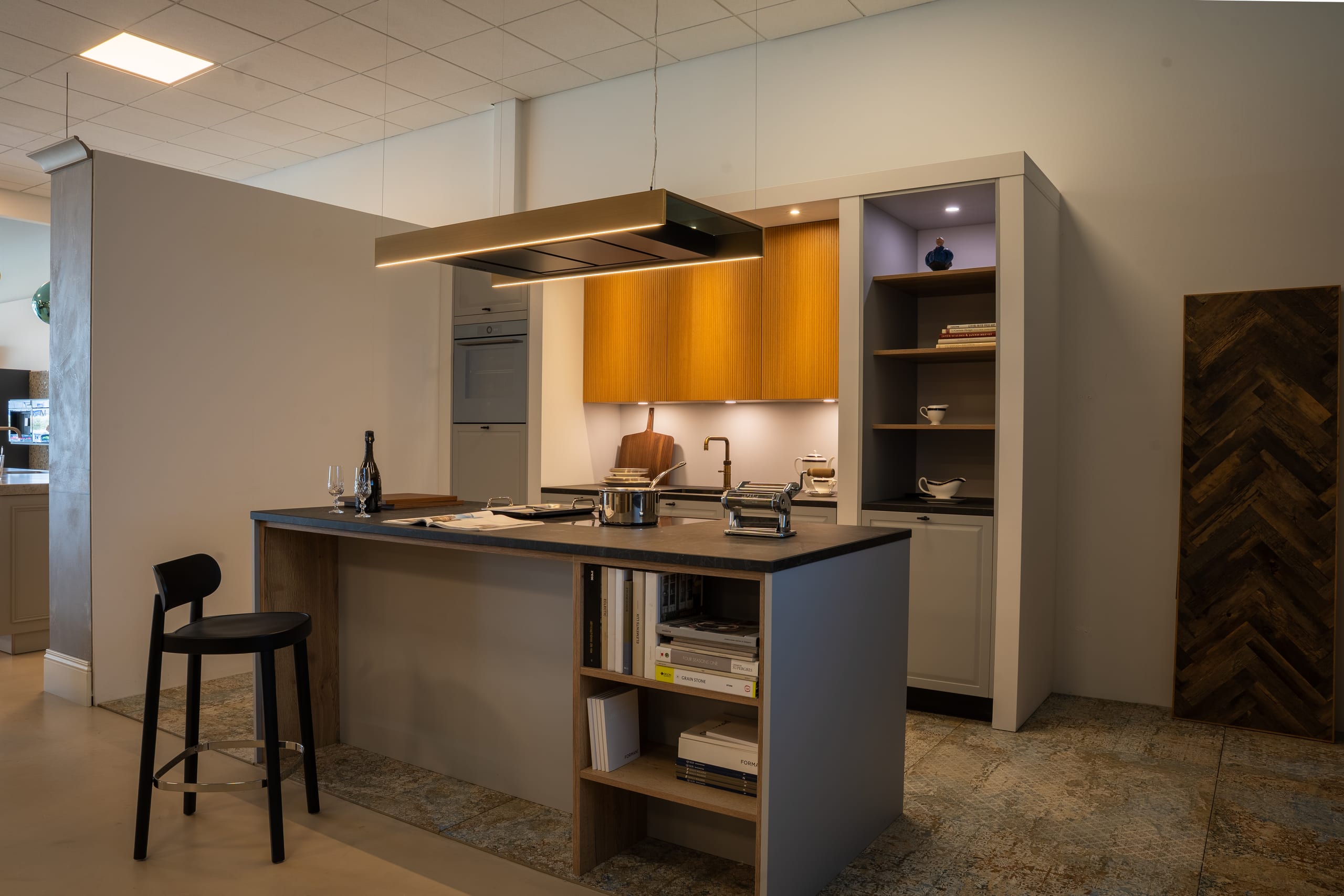 Showroomopstelling keuken met kookeiland en open boekenwand