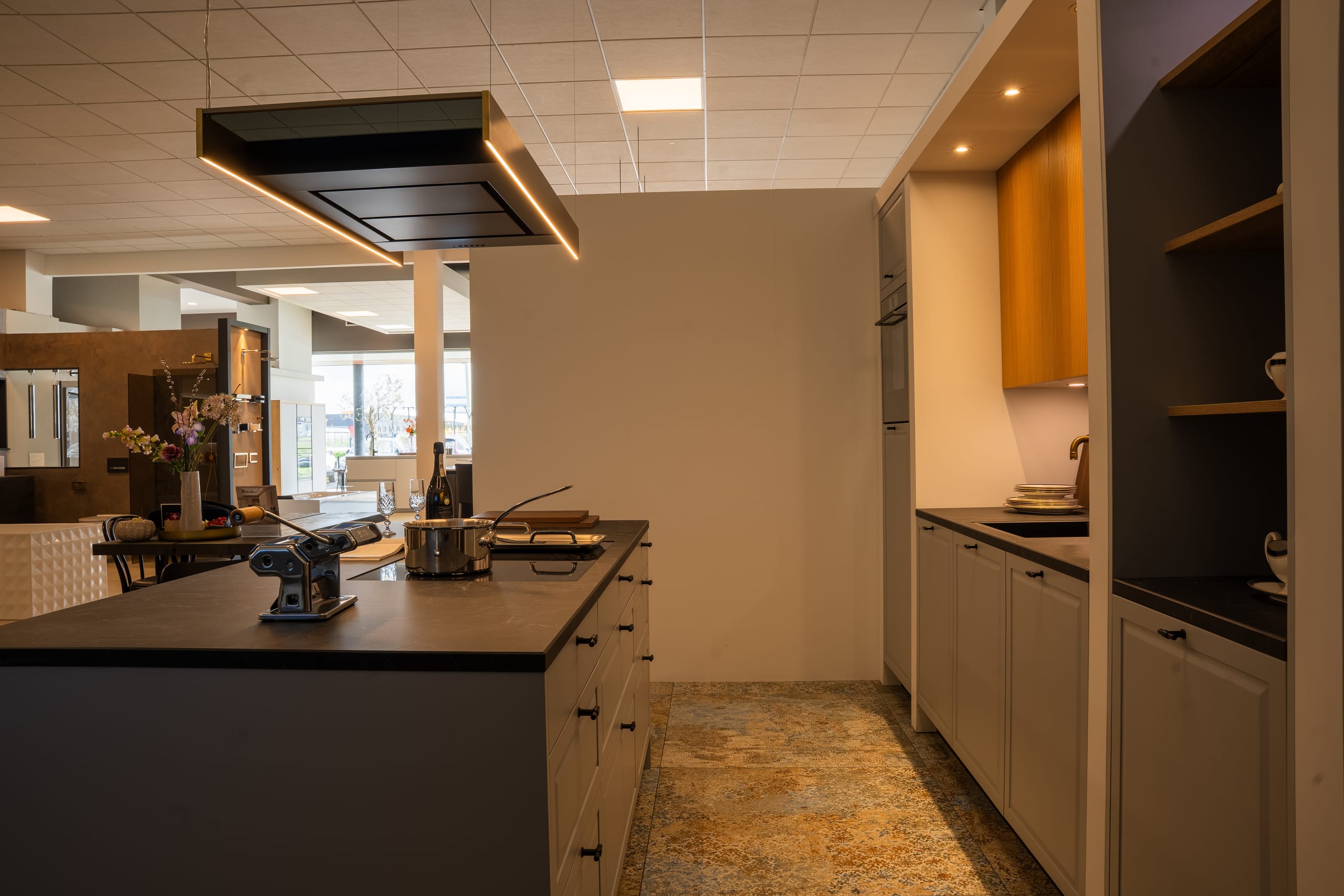 Showroomopstelling keuken met kookeiland, pastamachine en champagneglazen