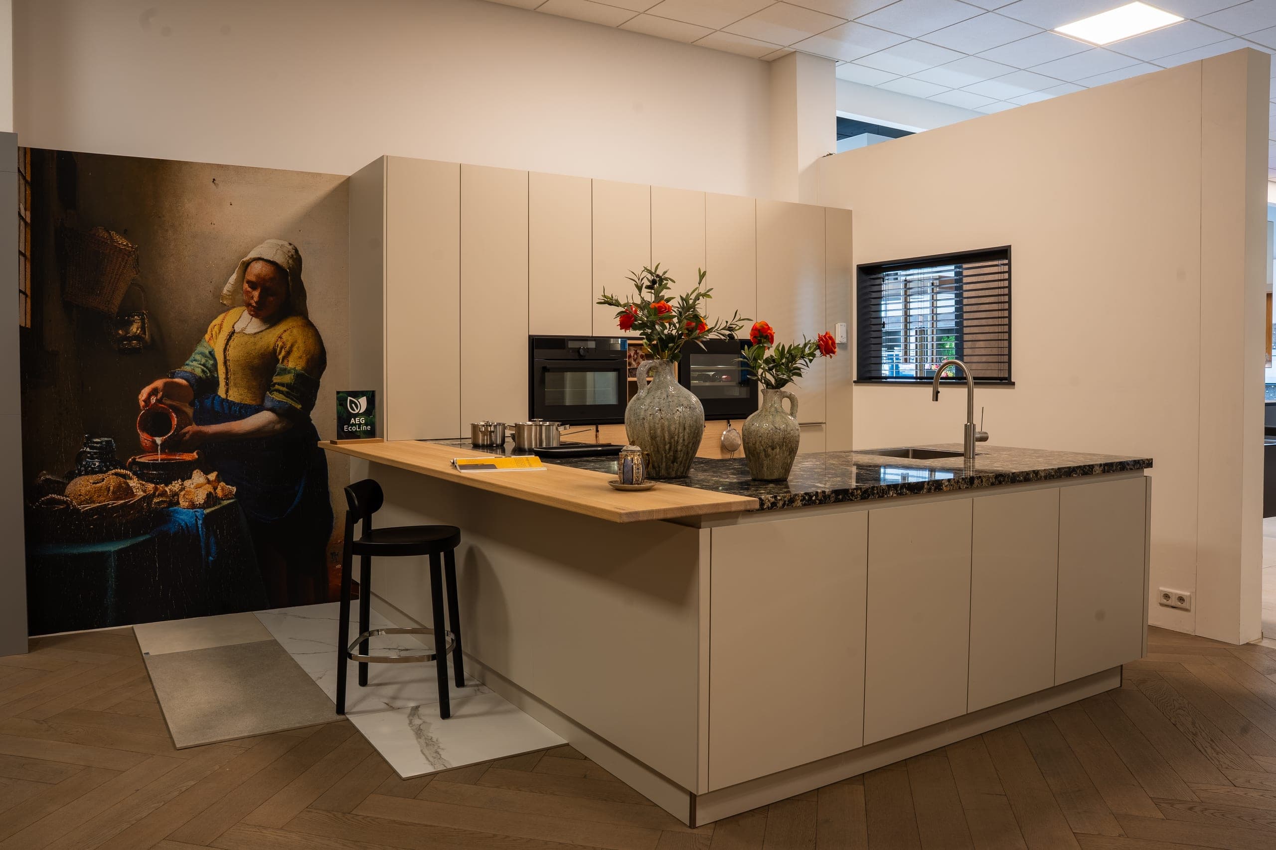Showroomopstelling keuken met ingebouwde AEG-apparatuur en Melkmeisje wanddecoratie