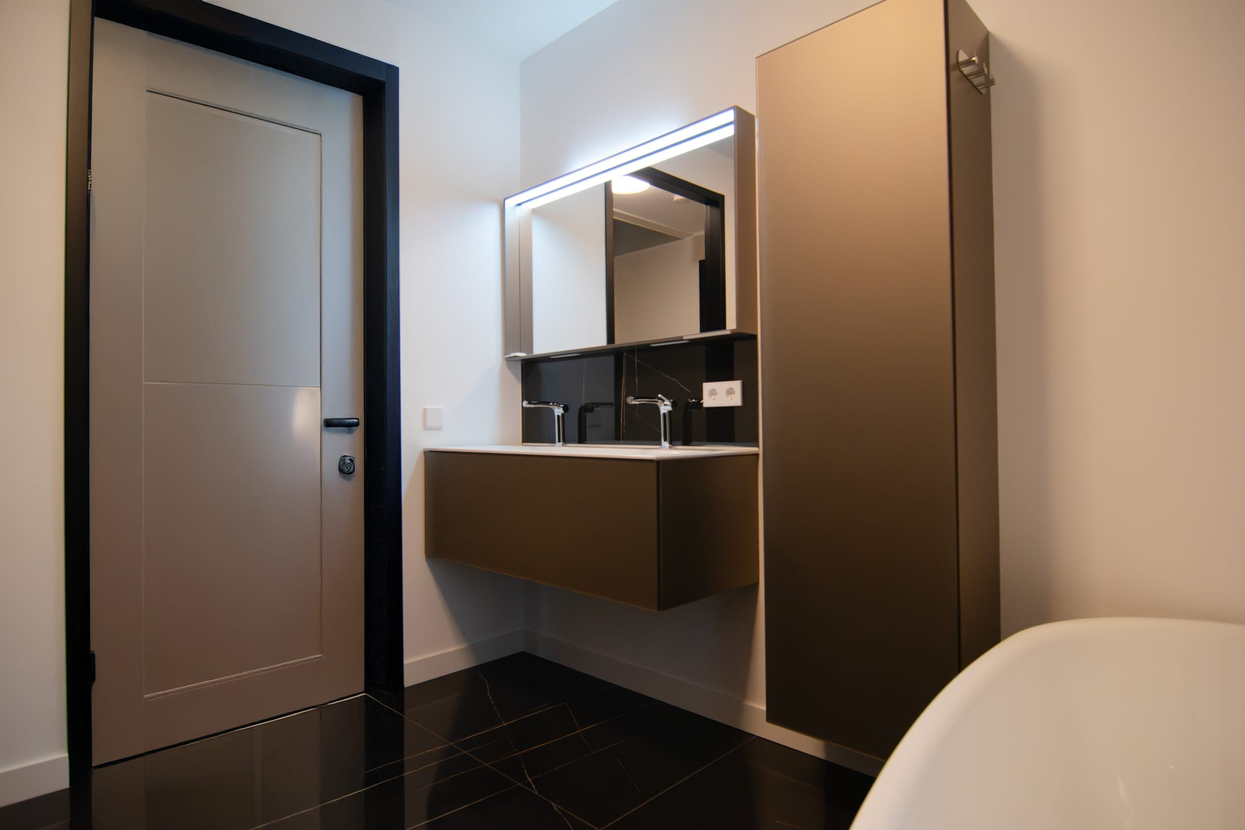 Wastafelmeubel met marmerlook wand en vrijstaand bad