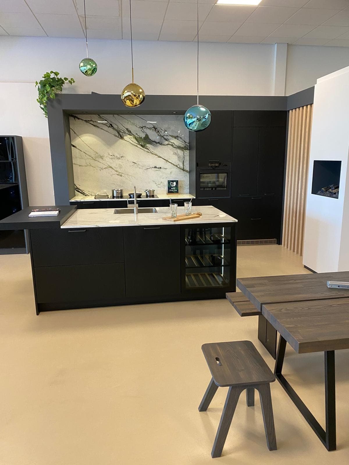 Kookeiland met marmerlook wand, wijnklimaatkast en gekleurde hanglampen