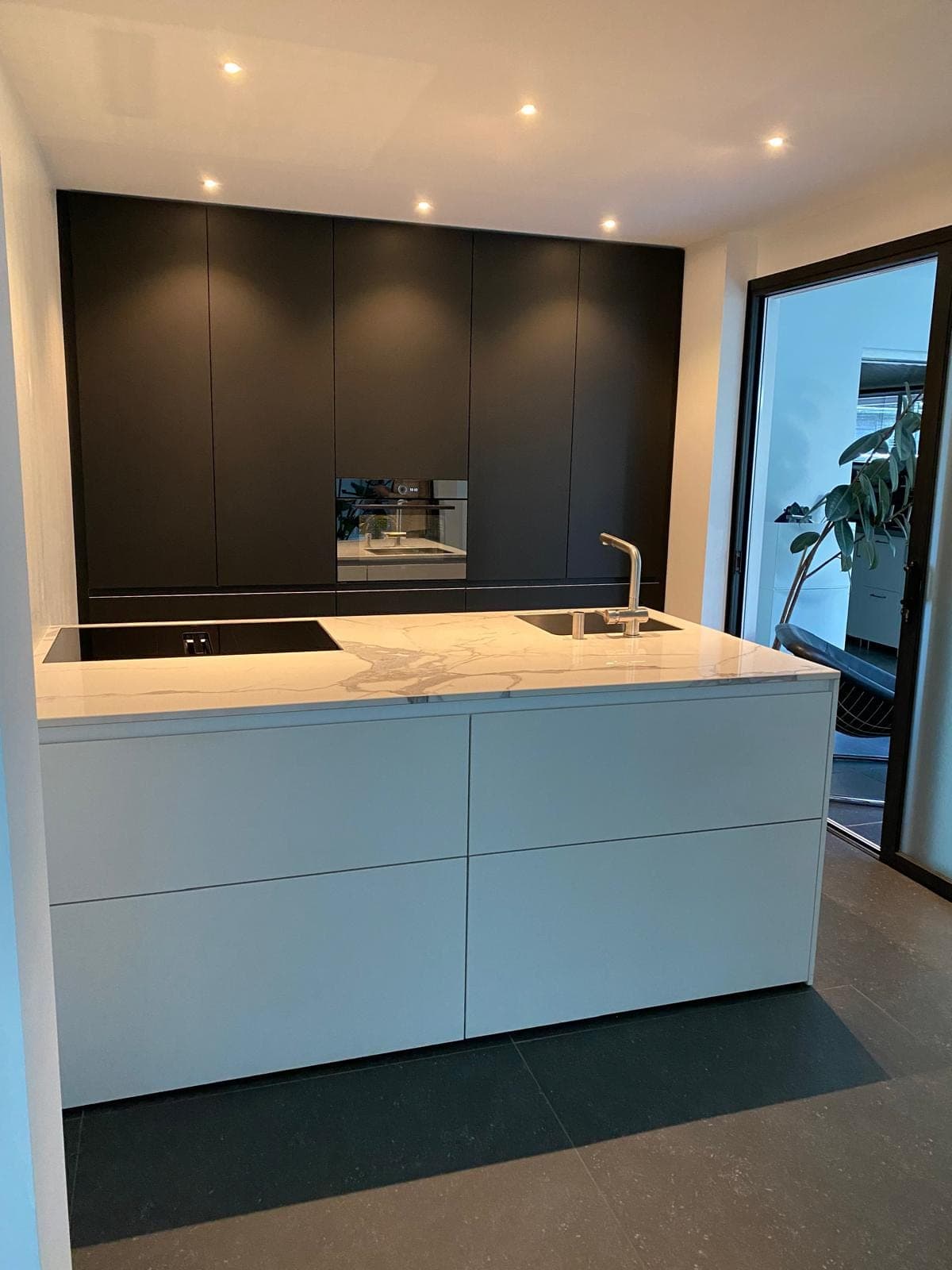 Zwarte keuken met marmerlook wand en messing kraan — Zoutelande